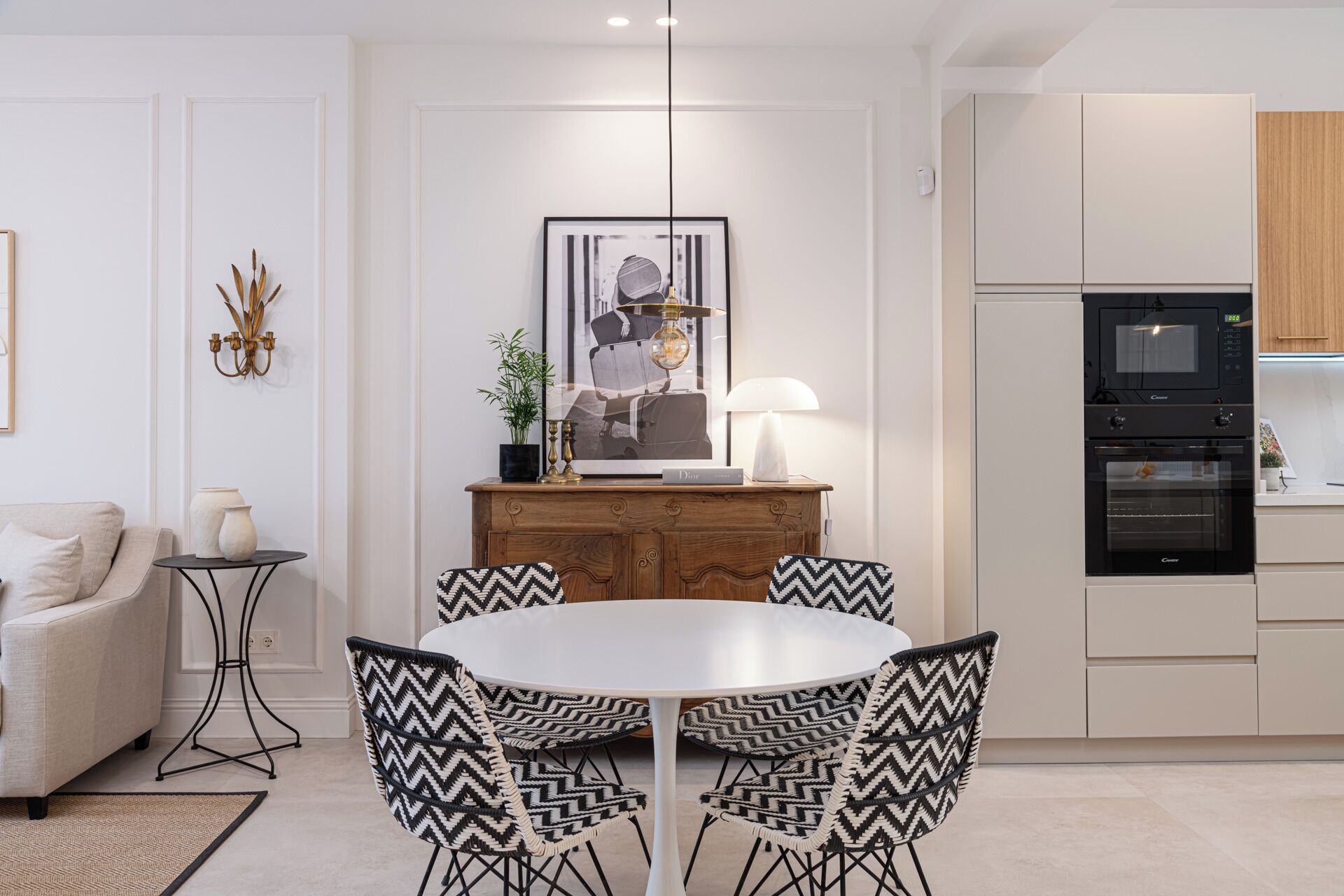 Una cocina moderna con comedor, que incluye una mesa redonda con sillas, un sofá y un elemento decorativo en la pared.
