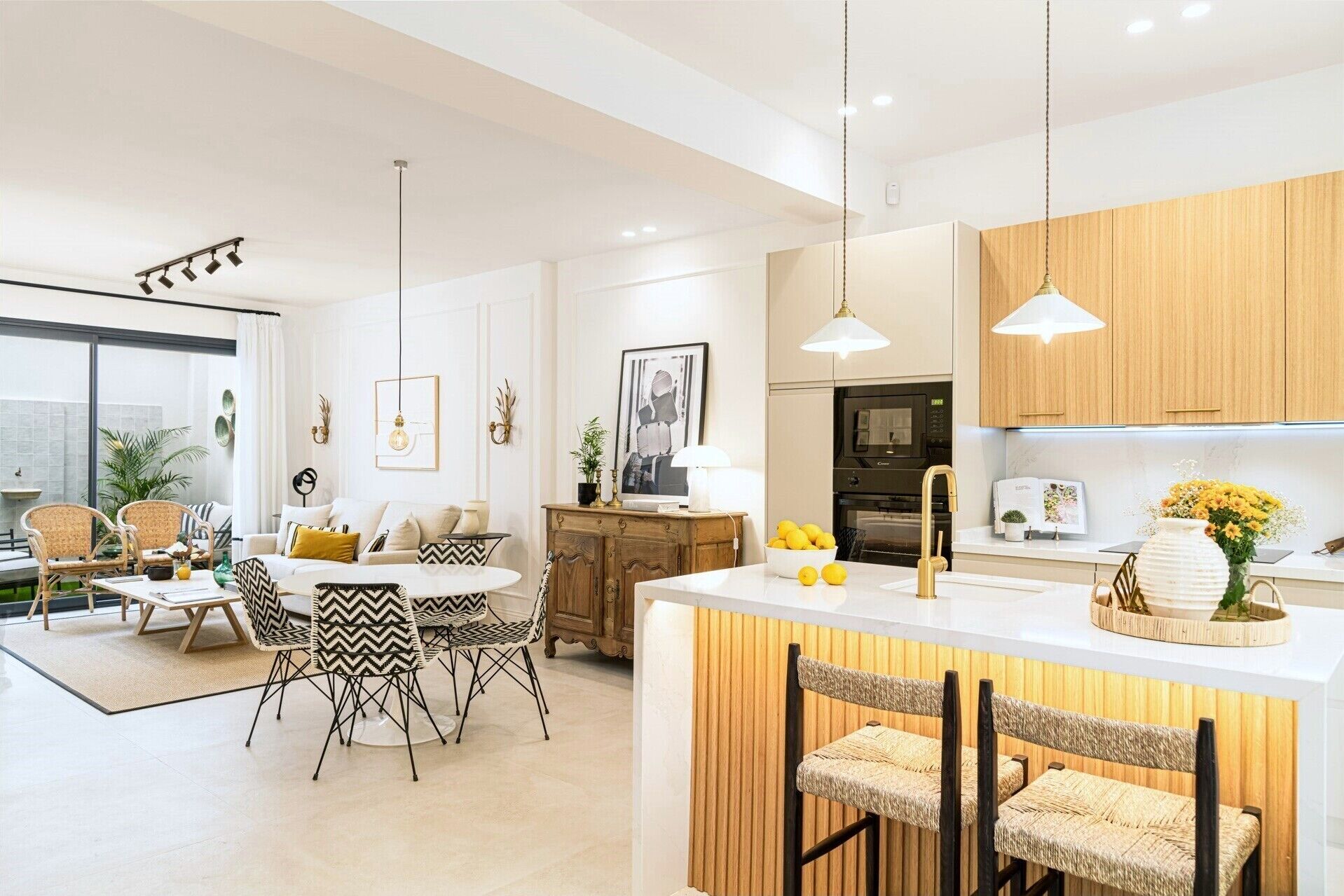 Una cocina moderna con una isla central, armarios de madera y un comedor con una mesa redonda y sillas.