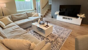 A modern living room with a sectional sofa, a coffee table, and a flat-screen TV mounted on a wall. - Urban Nest HTX (Houston)