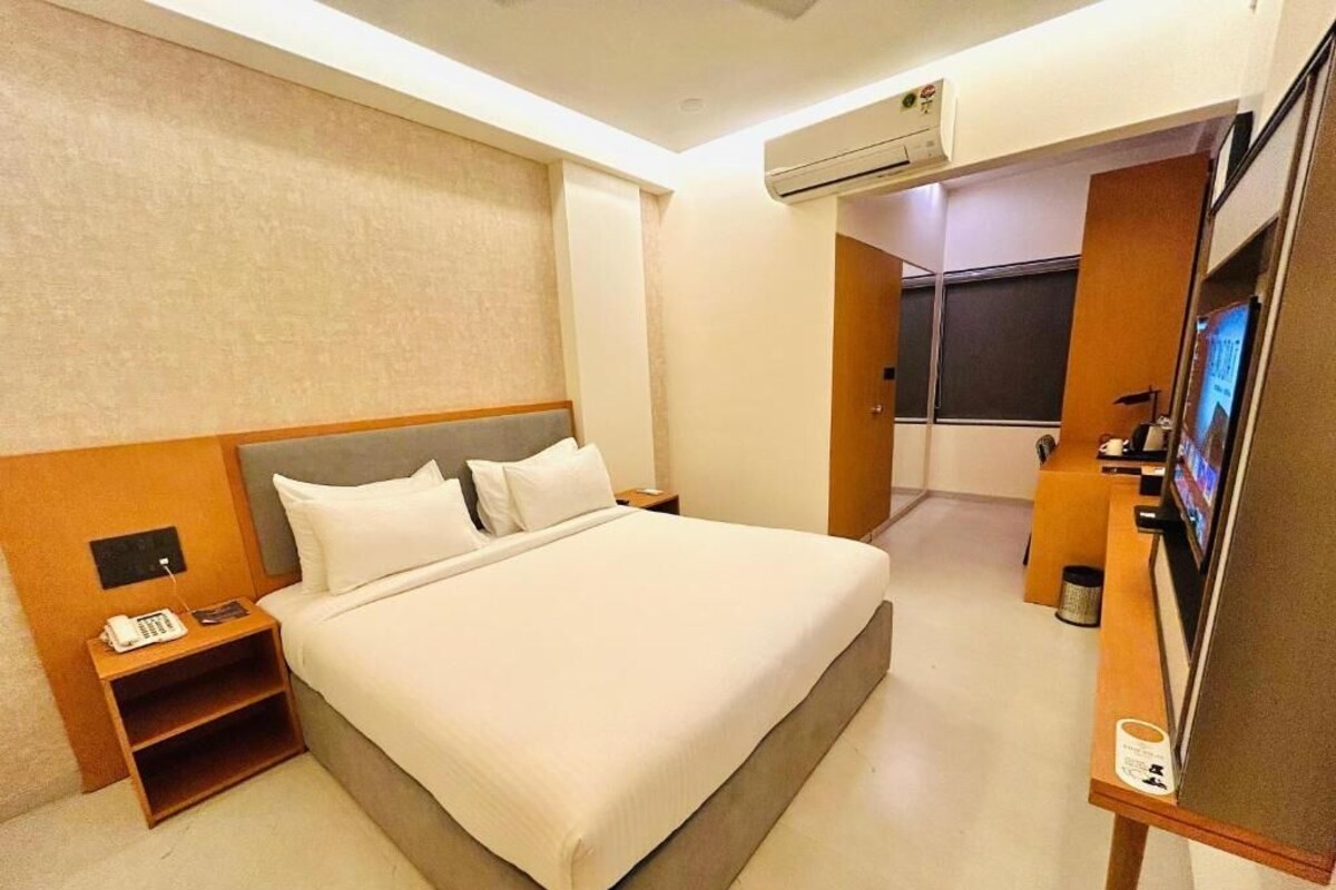 A hotel room with a large bed, a bedside telephone, a small table, and a television.