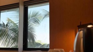A hotel room with a window view of palm trees, a coffee maker, and a cup on a tray. - HOTEL VIJAY VILAS (Jalna)