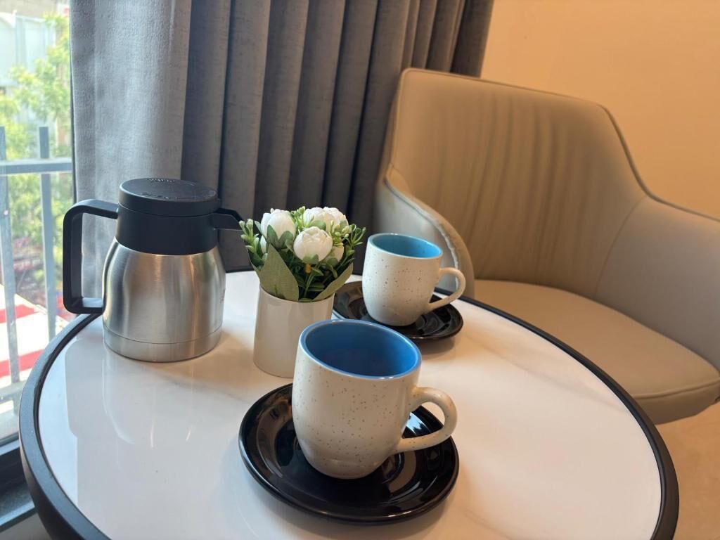 Une table avec une machine à café, deux tasses et une petite plante.