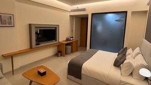 A modern hotel room with a bed, a TV, a desk, and a ceiling fan. - HOTEL VIJAY VILAS (Jalna)