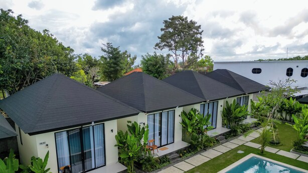 Un complexe résidentiel moderne comprenant plusieurs maisons, une piscine et une végétation luxuriante.