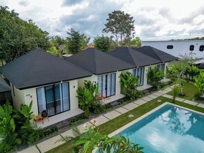 A modern residential complex with multiple houses, a swimming pool, and lush greenery. - Kula Uluwatu (Pecatu)