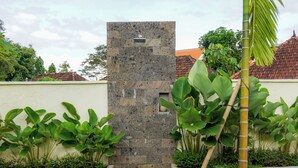 Un mur de pierre agrémenté d’une petite fenêtre, entouré d’une végétation luxuriante et d’une pelouse bien entretenue.