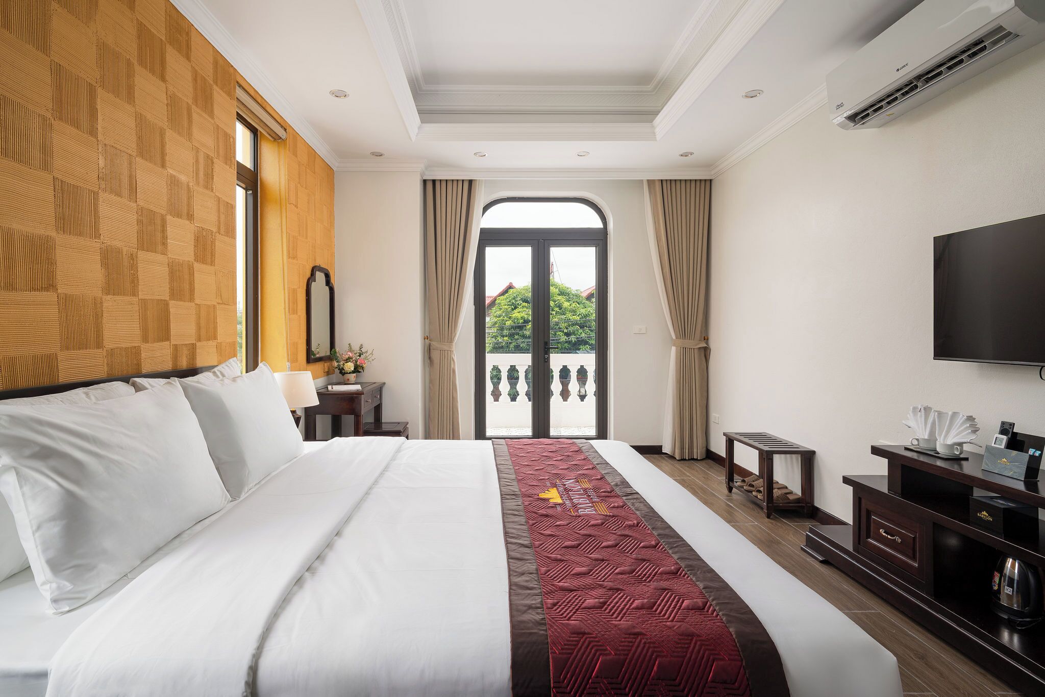 A hotel room with a large bed, a TV, a desk, and a balcony with a view.