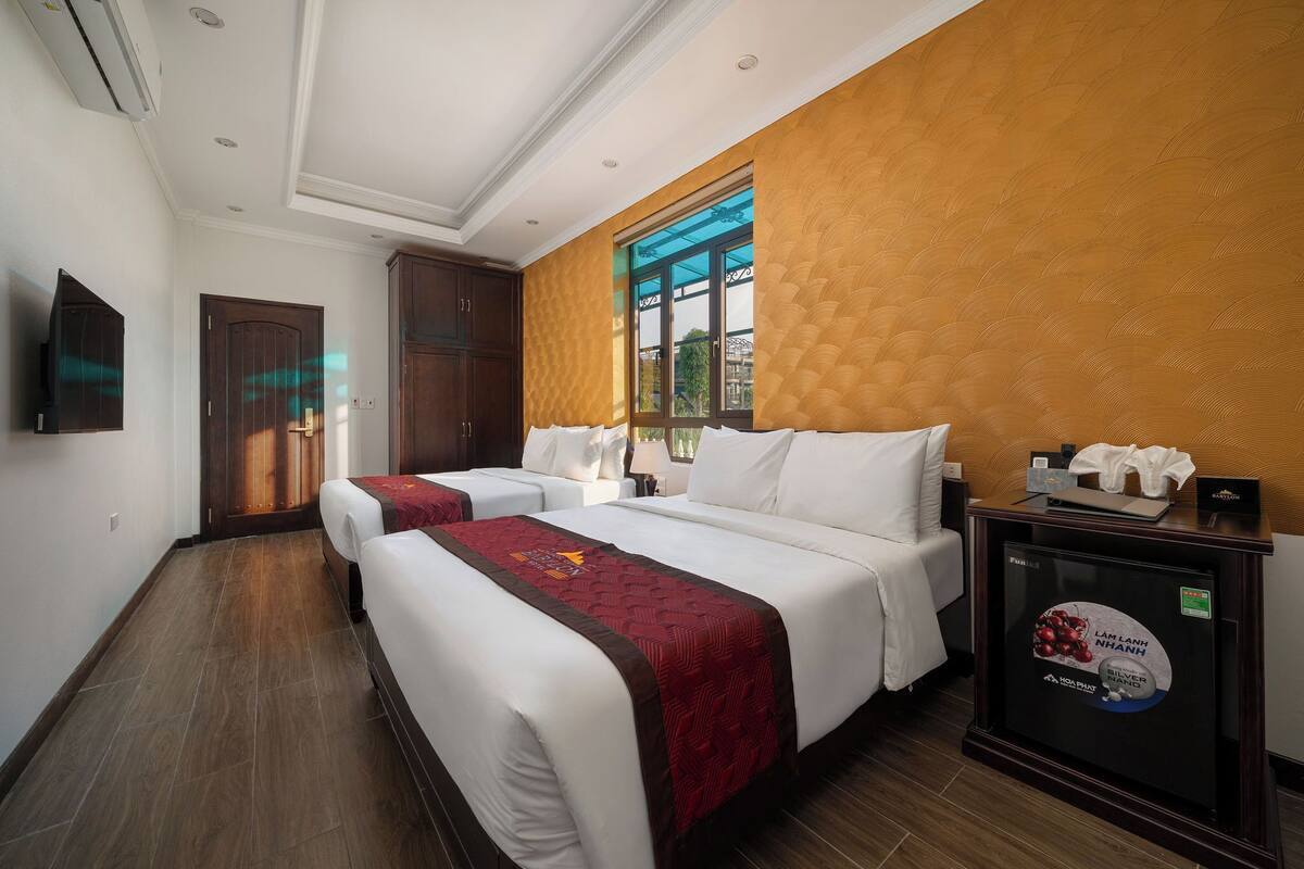 Habitación de hotel con dos camas, televisión, ventana y minibar.