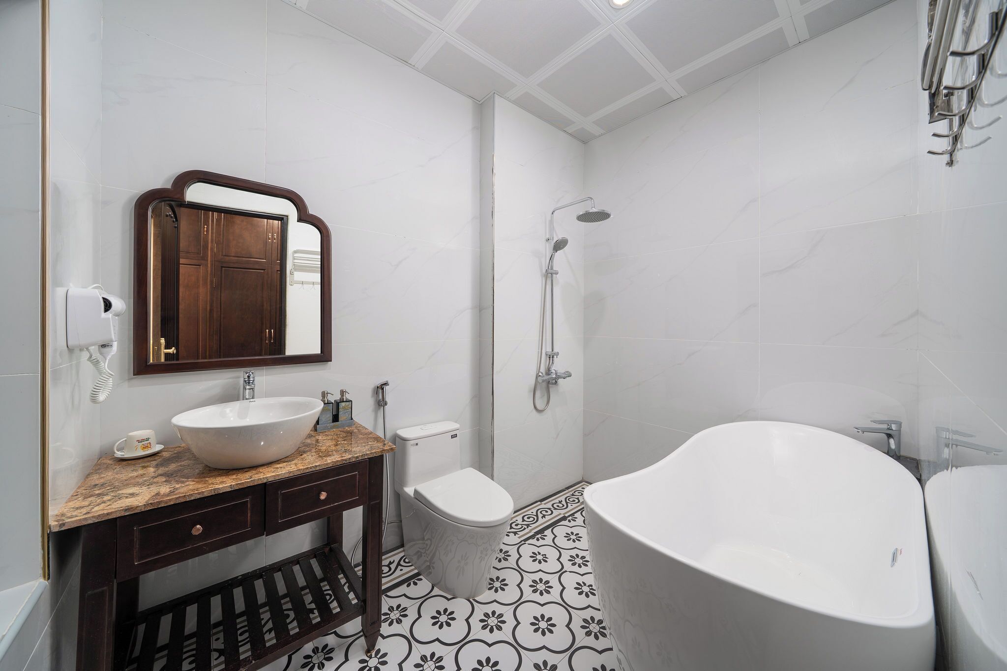 Un baño moderno con una bañera independiente, un lavamanos con encimera de mármol, un inodoro y una ducha con cabezal de ducha manual.