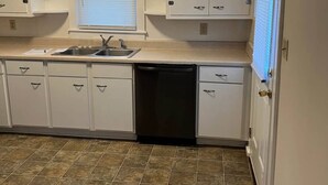 A kitchen with white cabinets, a sink, and a dishwasher. - Charming 2-bedroom house in lovely Columbia with AC/ WiFi and smart tv. Backyard (Columbia)