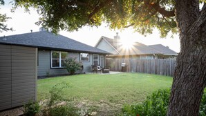 A residential backyard with a lawn, a barbecue area, and a wooden fence.