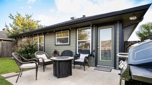 A patio with outdoor furniture, a grill, and a covered area with sliding glass doors.