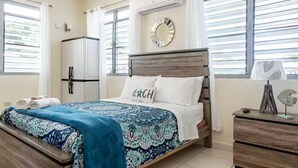 Quarto com cama, mesa de cabeceira, espelho e janela com persianas.