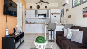 Uma sala de estar moderna com um sofá marrom, uma mesa de centro branca e uma TV na parede.