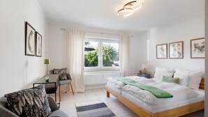 Un dormitorio moderno con cama, escritorio, silla y ventana con cortinas.
