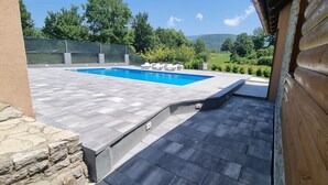 Una piscina con borde de piedra, rodeada por un muelle de madera y muros de piedra.