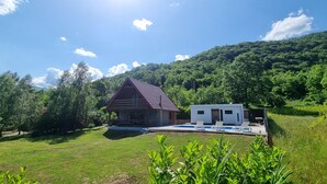 Ein Haus mit Schwimmbad, umgeben von üppiger Vegetation und einem bewaldeten Hügel.