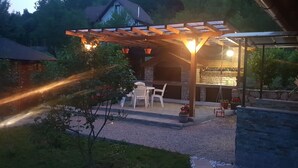 Un área de patio exterior con una pérgola, asientos y una zona de barbacoa.