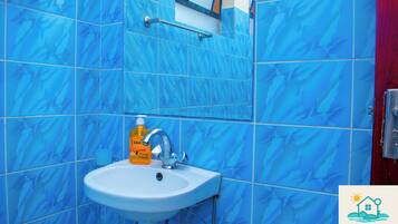 Een badkamer met blauwe marmeren tegels, een witte wastafel, een spiegel en een zeepdispenser.