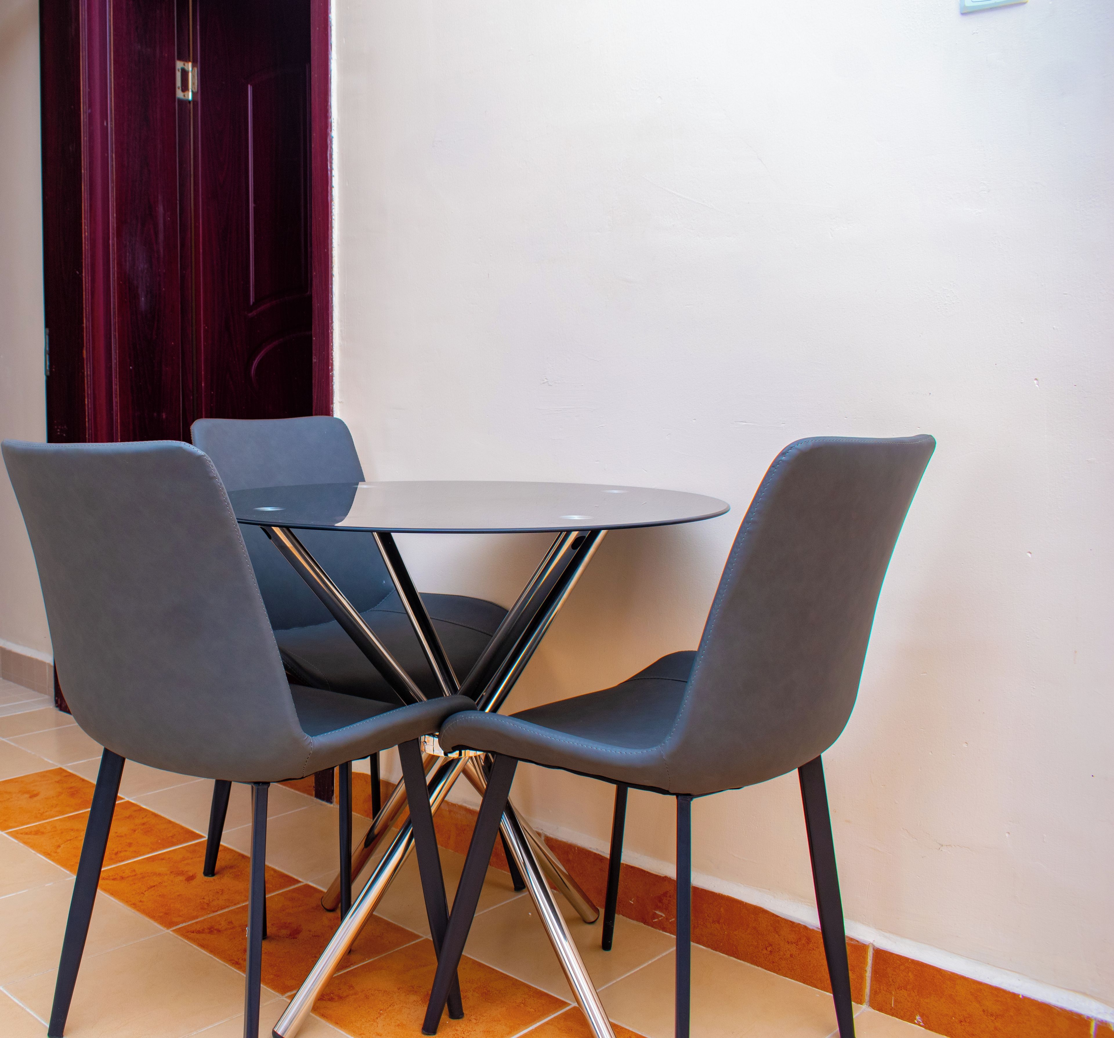 Een eetgedeelte met een ronde tafel en vier grijze stoelen.