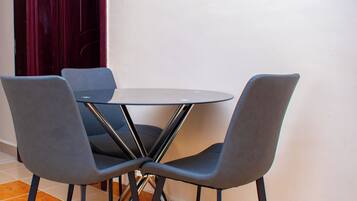 Een eetgedeelte met een ronde tafel en vier grijze stoelen.