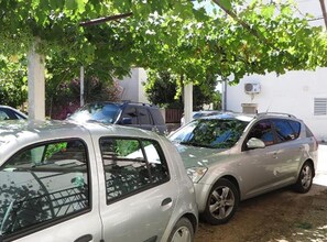 Ein Parkplatz mit mehreren unter einem Baum stehenden Autos.