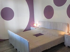 Een slaapkamer met een bed, nachtkastjes en een muur met cirkelvormige patronen.
