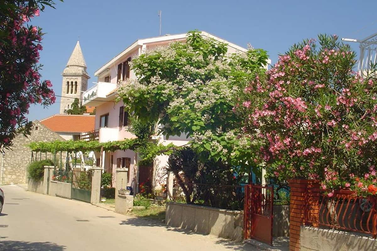 A building with a tower, surrounded by flowering trees and a clear sky.