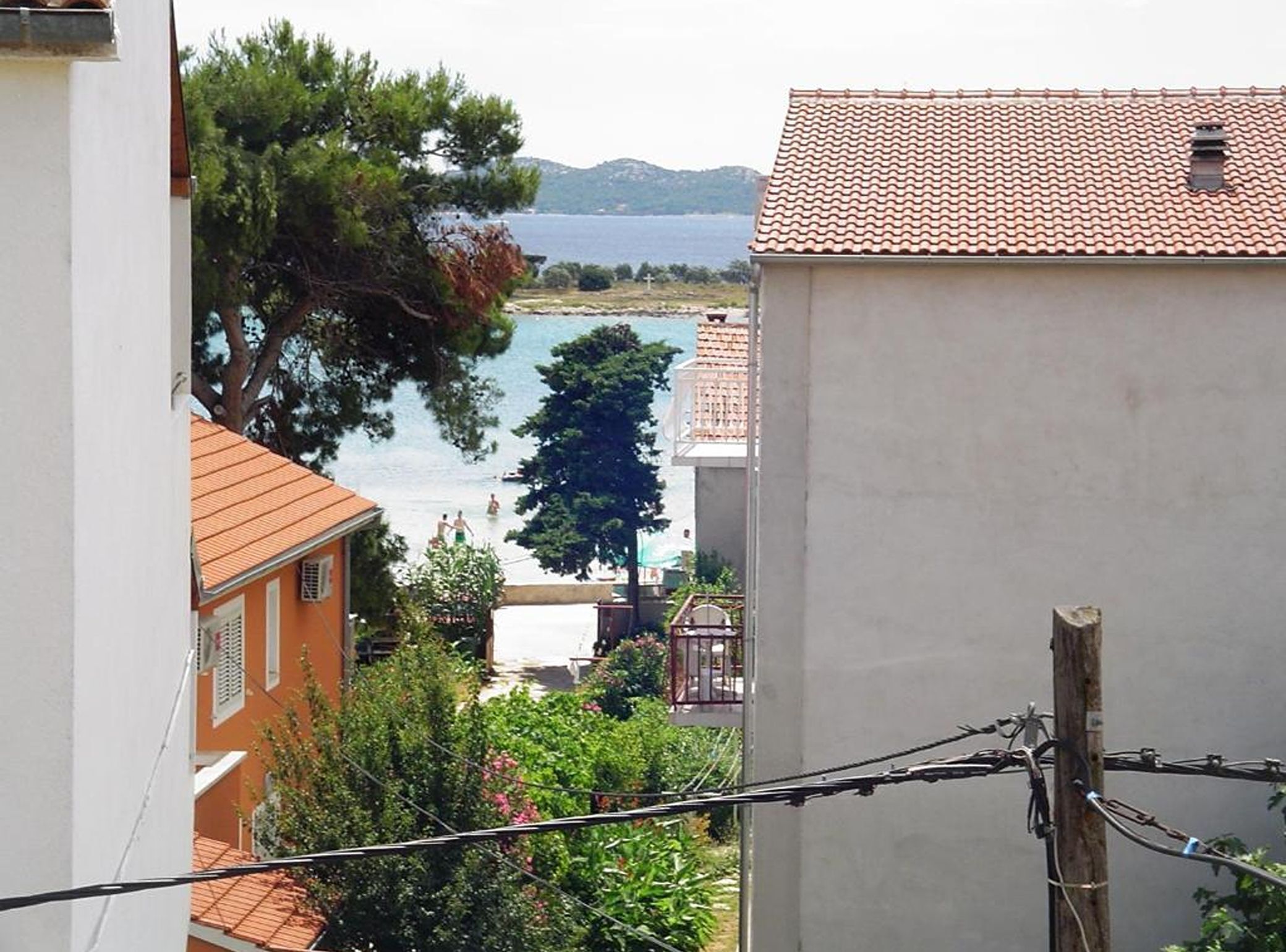 A view of a coastal area with buildings, a tree, and a body of water.