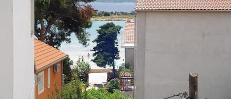 Blick auf eine Küstenlandschaft mit Gebäuden, einem Baum und einem Gewässer.