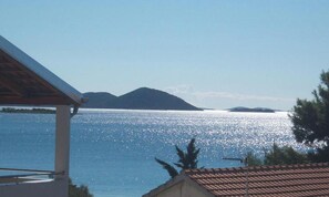 Uitzicht op de kust, met heldere lucht, een waterlichaam en verre bergen.