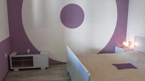 A bedroom with a bed, a nightstand, a dresser, and a wall with a large circular design. - Apartments A&N Pakoštane (Pakostane)