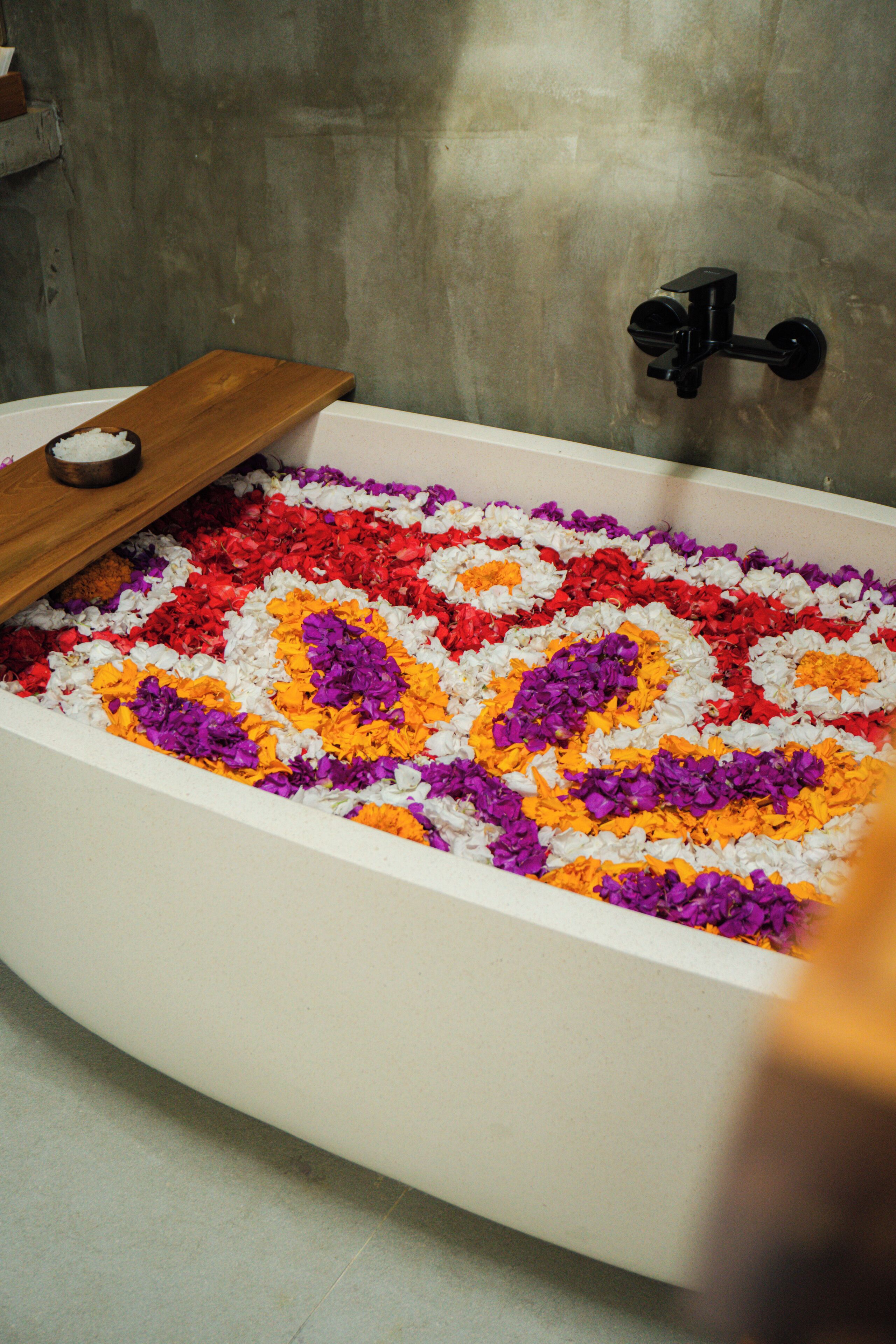 A bathtub filled with colorful flower petals.