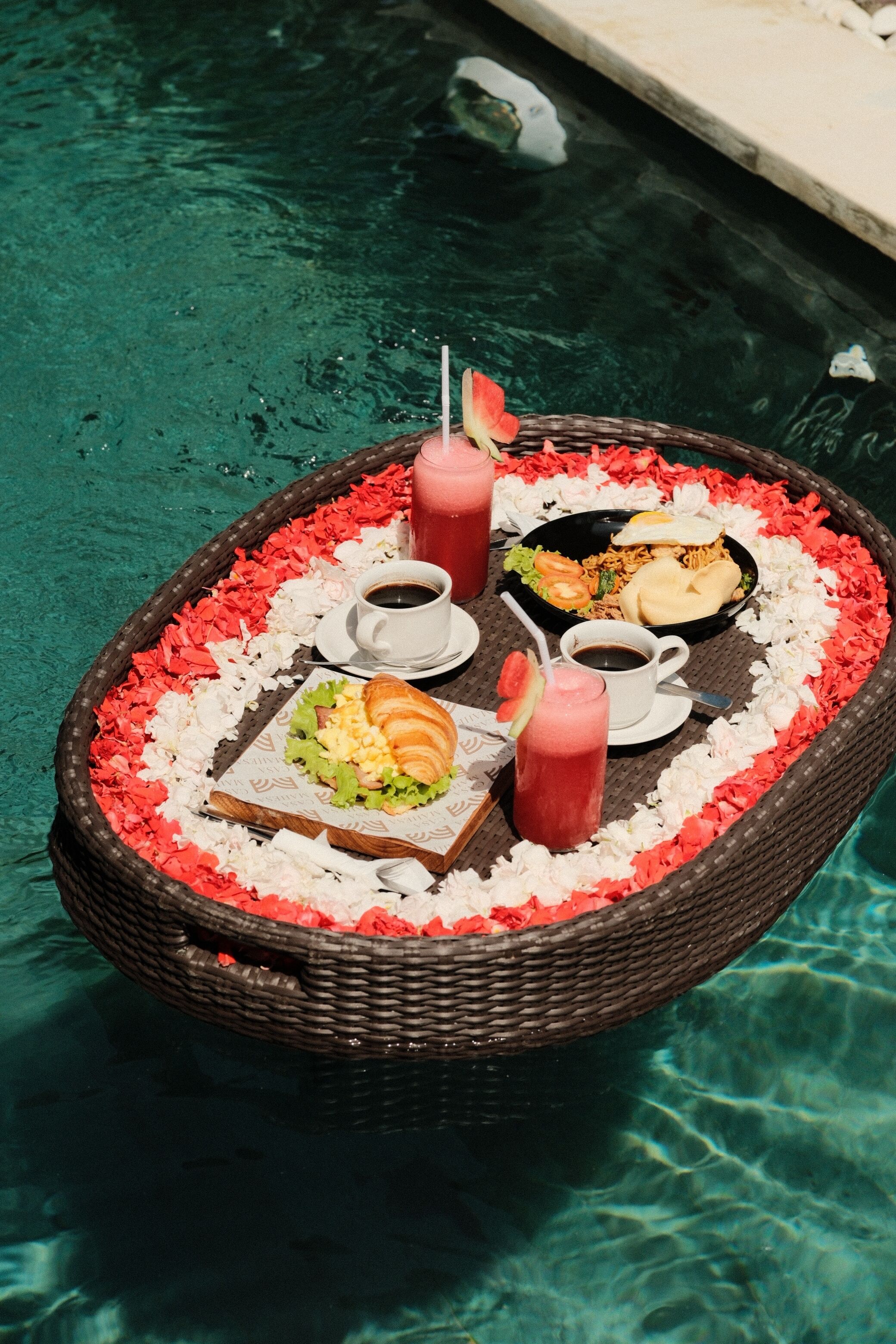 A floating dining setup with food and drinks on a poolside.