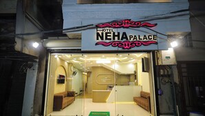The entrance of Hotel Neha Palace with a reception desk, two sofas, and a welcome mat. - Hotel Neha Palace (Ujjain)