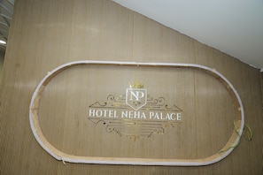 A sign for HOTEL NEHA PALACE with a crown emblem and the letters "NP" above the name.
