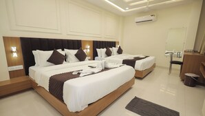 A hotel room with two beds, a wooden headboard, white bedding, and a small desk with a chair. - Hotel Neha Palace (Ujjain)