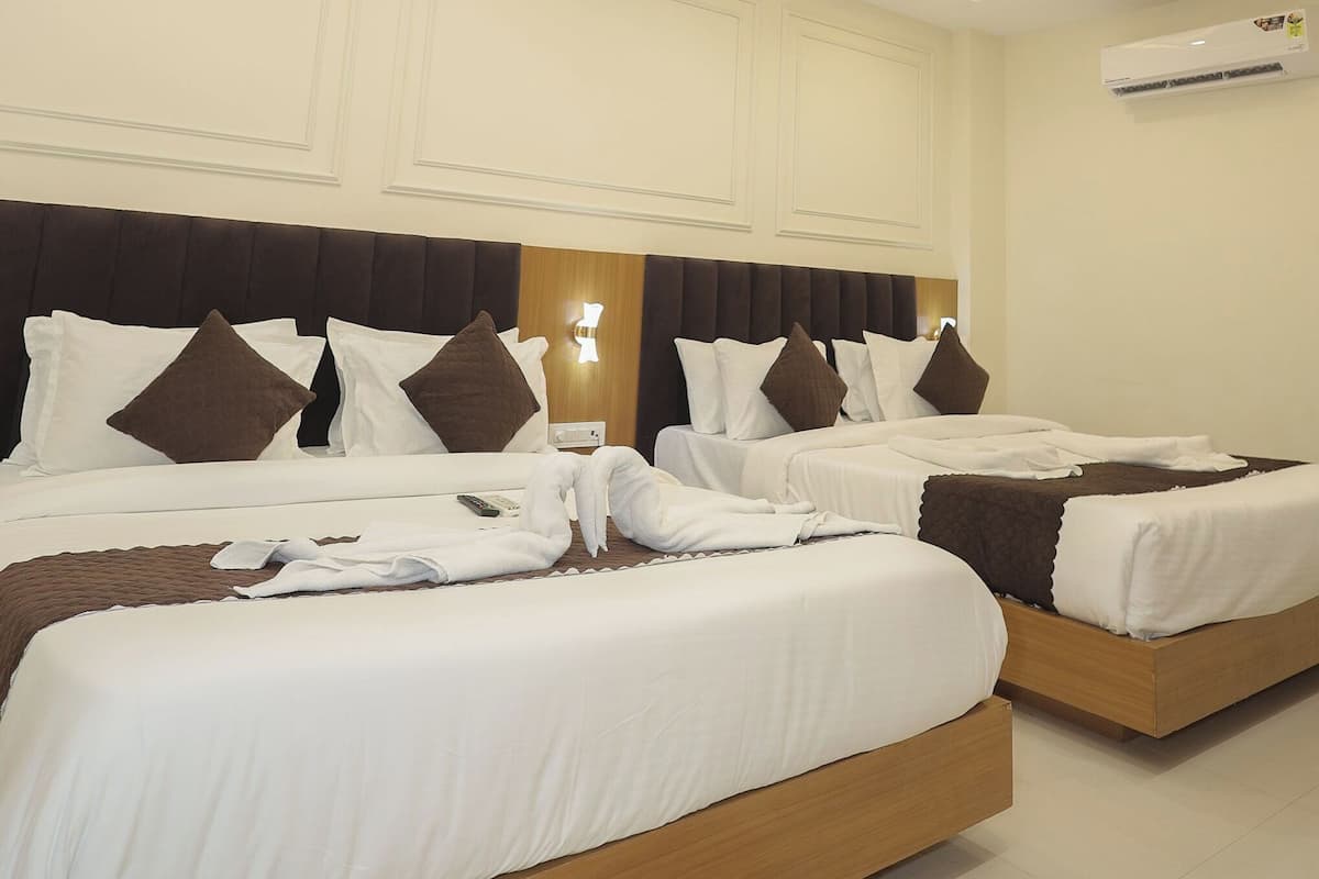Habitación de hotel con dos camas, ventilador de techo, iluminación empotrada y aire acondicionado.