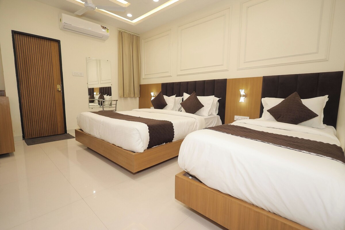 A hotel room with two beds, a wooden door, a mirror, and a ceiling fan.