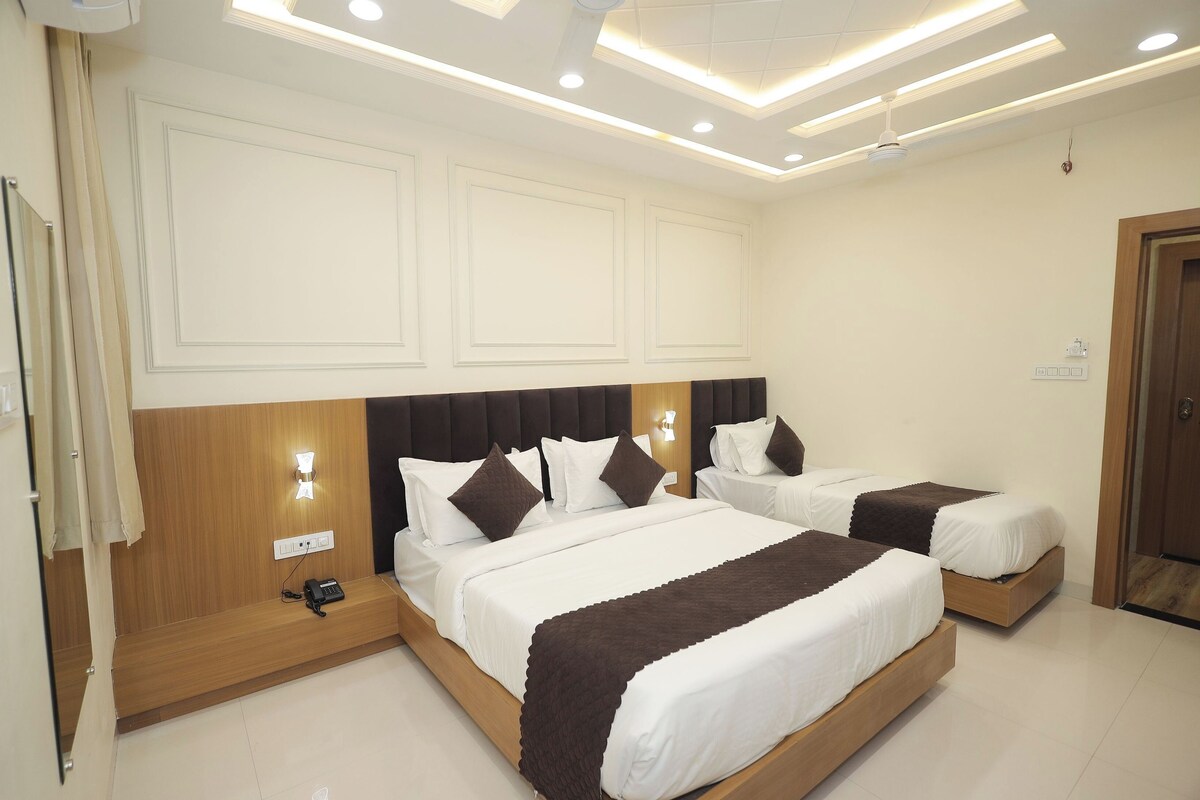 A hotel room with two beds, a wooden headboard, bedside lamps, and a ceiling light fixture.