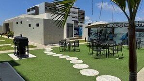 An outdoor patio with artificial grass, a barbecue grill, and outdoor seating. - Depa in Cerritos near the Beach with Great Amenities By GPS (Mazatlán)