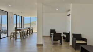 A spacious indoor area with a long table and chairs, a high ceiling, and large windows offering a view of the outdoors. - Depa in Cerritos near the Beach with Great Amenities By GPS (Mazatlán)