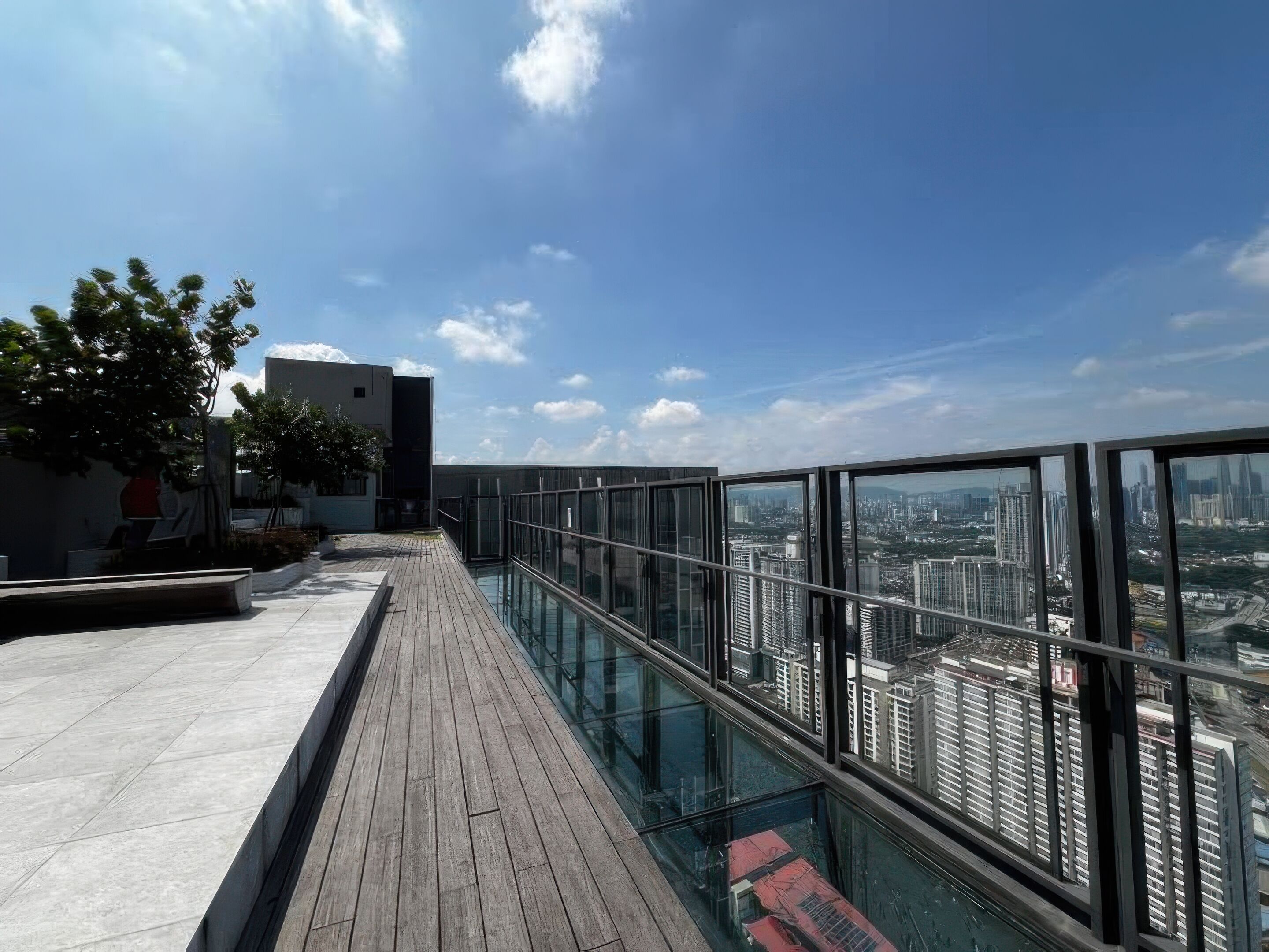 A rooftop terrace with a glass balustrade overlooking a cityscape.