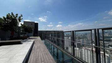 A rooftop terrace with a glass balustrade overlooking a cityscape.