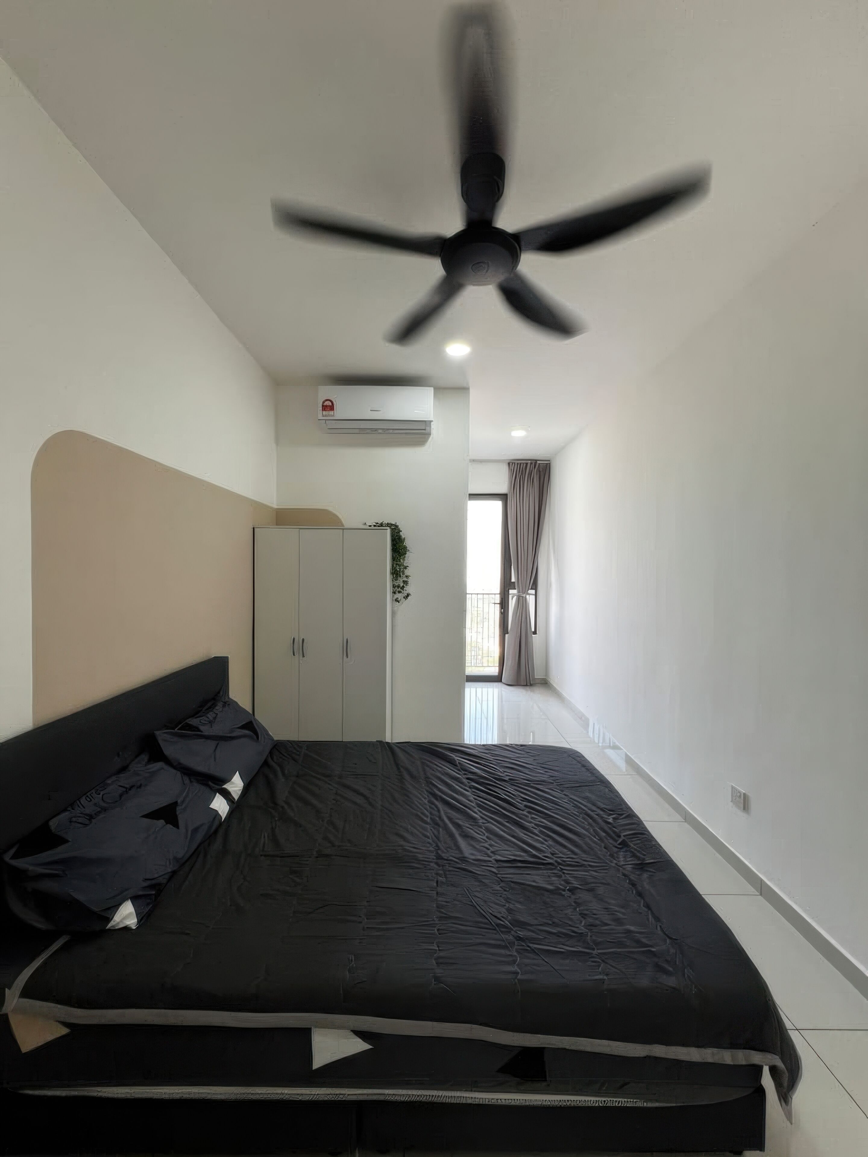 Una camera da letto con un letto, una ventola a soffitto, un condizionatore e vista su un balcone.