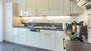 A modern kitchen with white cabinets, a stainless steel sink, and a built-in dishwasher.