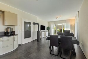 A modern kitchen with a dining area, a built-in oven, and a large window.