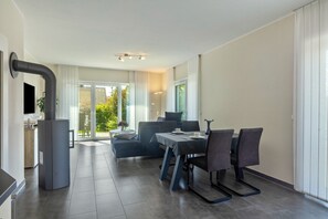 A modern kitchen with a built-in stove, a dining area with a table and chairs, and a sofa.