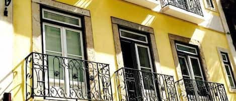 A yellow building with multiple balconies and arched doorways.