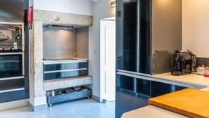 A modern kitchen with a built-in oven, a stainless steel range hood, and a coffee maker on the counter. - Stylish 2BR Loft w/ Views • Av. Liberdade & Metro (Lisbon)